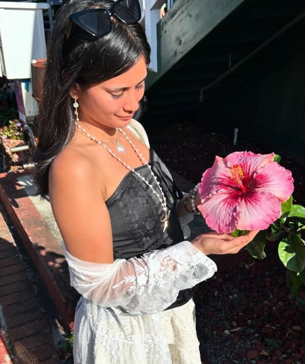 girl in black shoulderless top and white skirt holding hibiscus flower